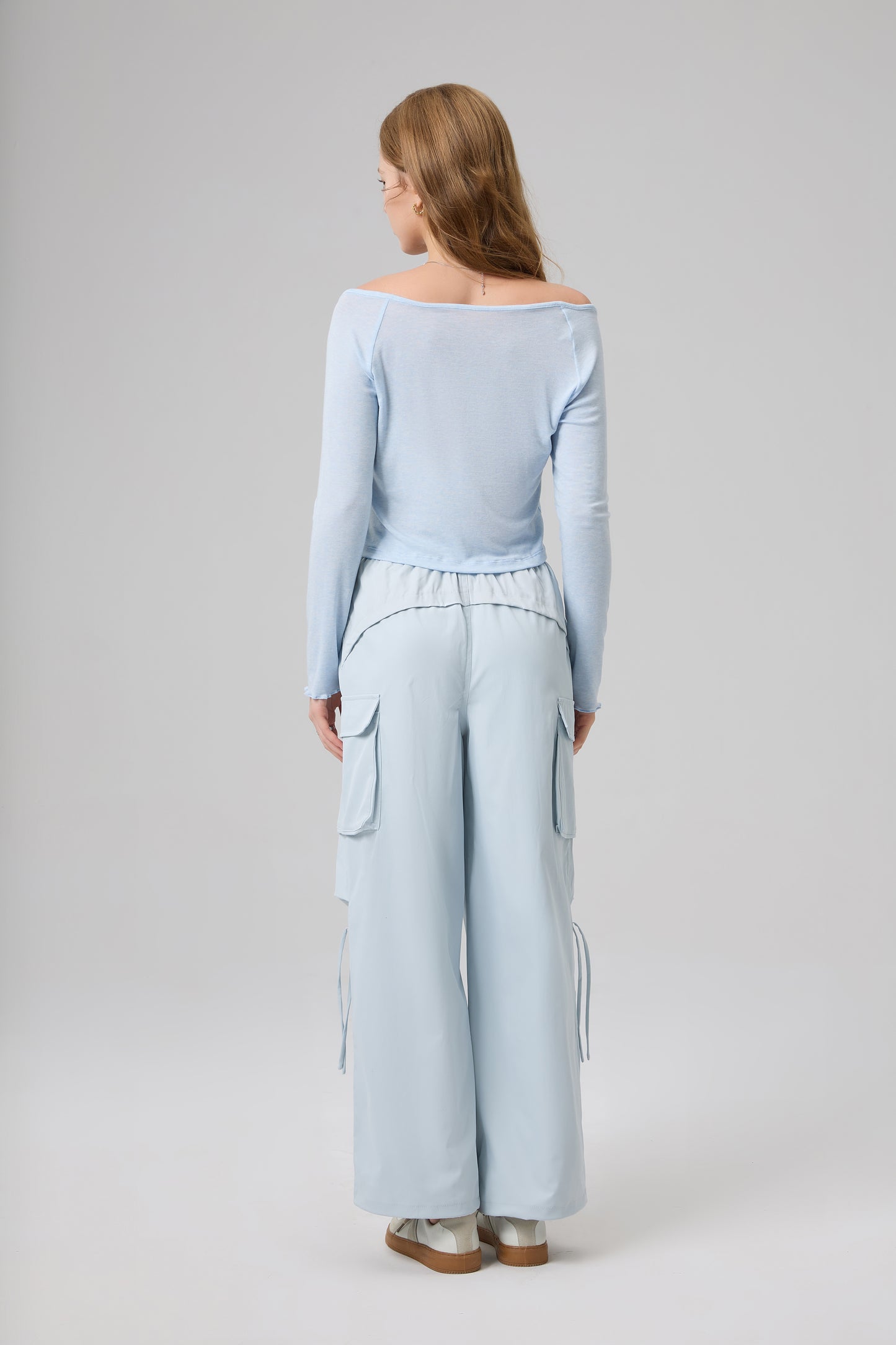 Woman wearing a light blue outfit with wide-leg pants on a white background