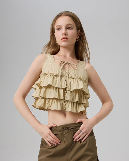 Woman wearing a layered ruffled top and high-waisted pants on a plain background