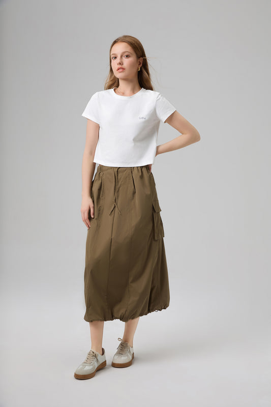 Model wearing The Lethe Logo Tee in Star White with olive cargo skirt, casual women’s minimalist cotton cropped tee.