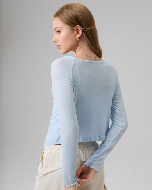 Woman wearing a light blue long-sleeve top against a plain background