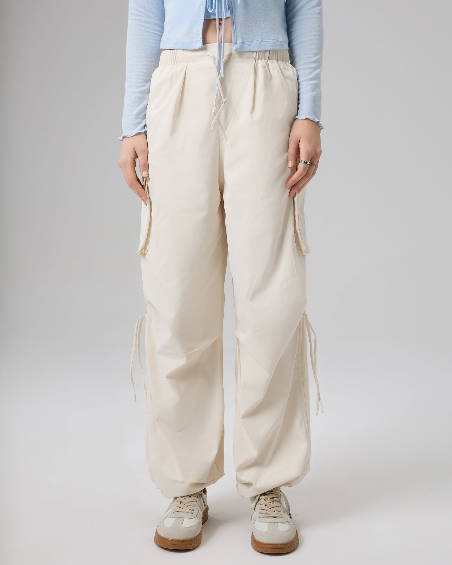 Person wearing light blue long-sleeve top and beige wide-leg pants on a plain background