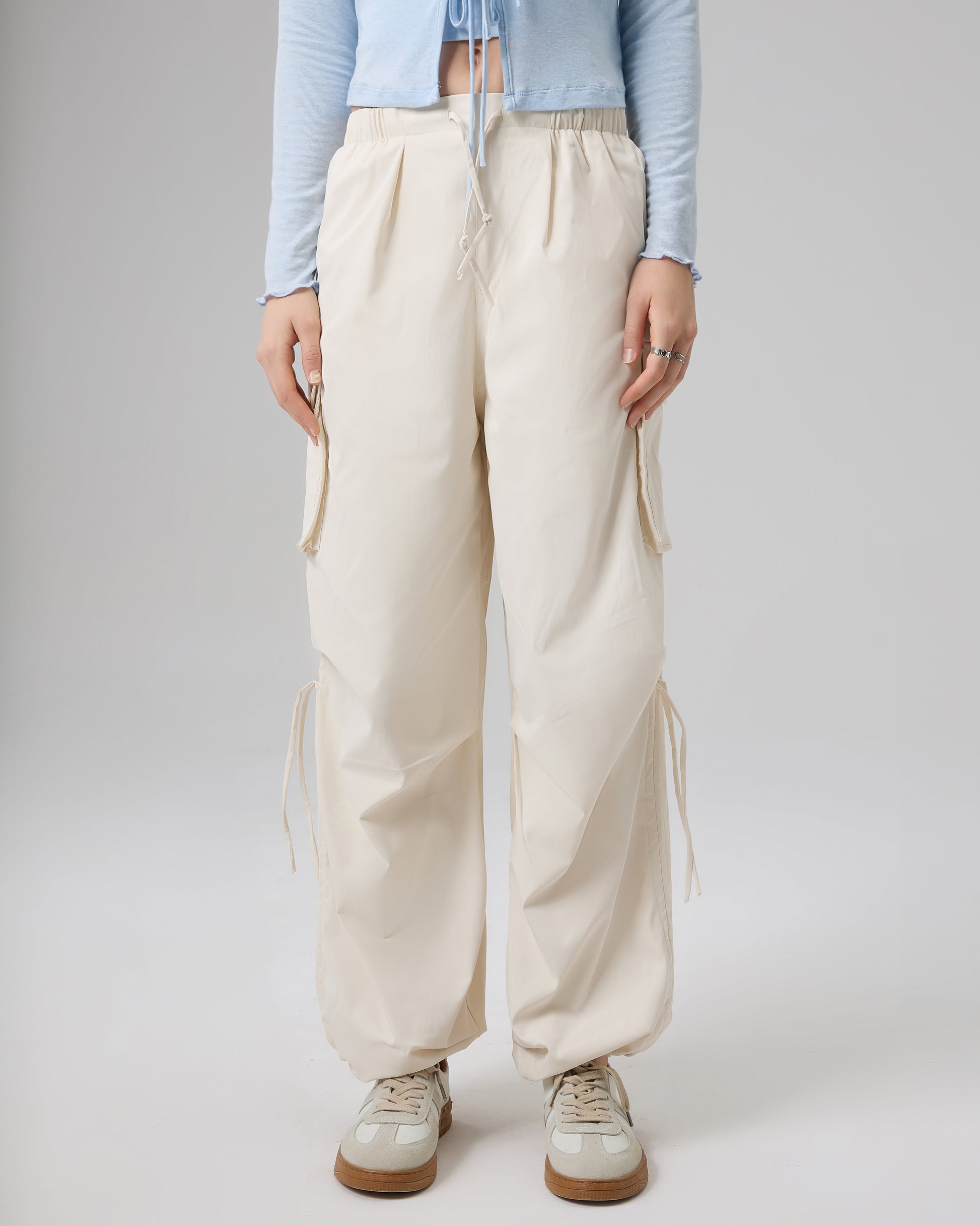 Person wearing light blue long-sleeve top and beige wide-leg pants on a plain background