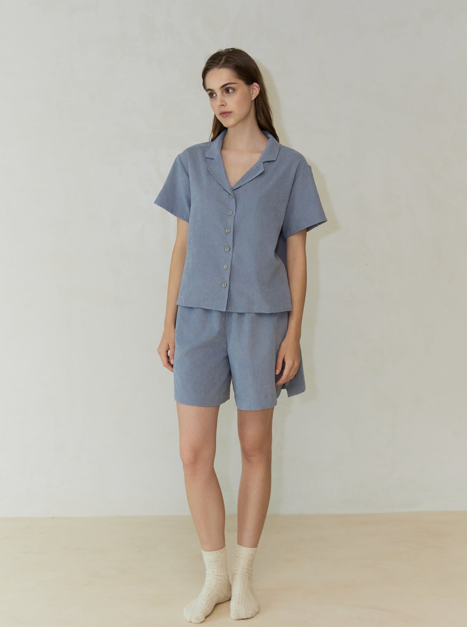 A female model wearing a silt green short-sleeved shirt and matching shorts.