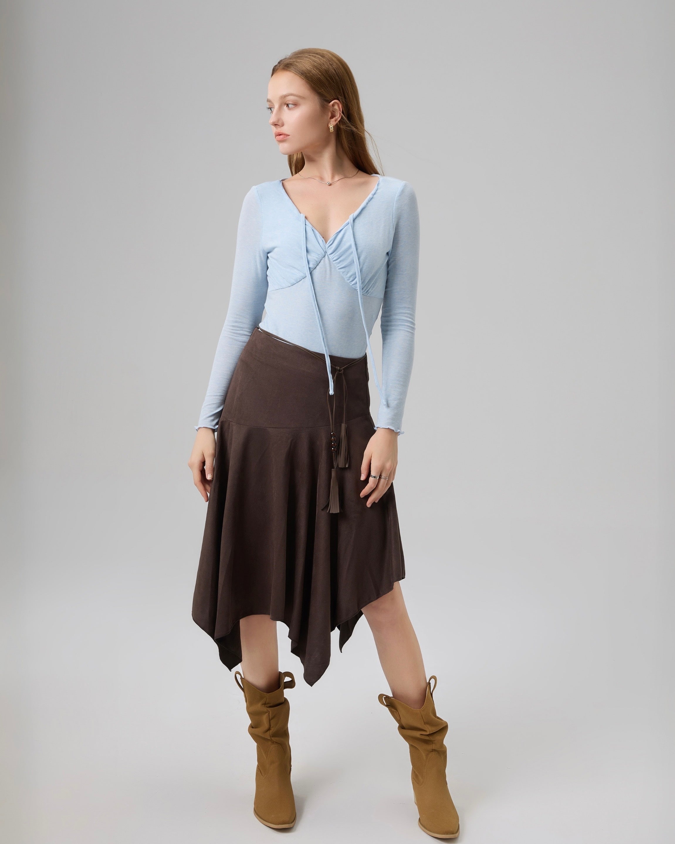 Full-body image of model styling The Knit Reverie Flowing Top with a brown skirt and tan boots.